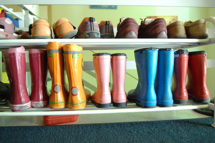 Ein geordnetes Schuhregal. Oben stehen Halbschuhe, unten Gummistiefel